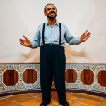 A professional musician, fully clothed in modest, traditional Portuguese attire, stands on a small, softly lit stage in a classic, cozy Fado house in Lisbon. The musician's expression conveys deep emotion and connection to the music's soul as they perform, surrounded by an intimate and authentic cultural atmosphere. Perfect anatomy, natural pose, well-formed hands, correct proportions, professional photography, high quality, safe for work, appropriate content, family-friendly.